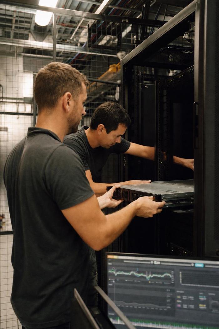 Deux techniciens glissent un serveur dans une baie de colocation