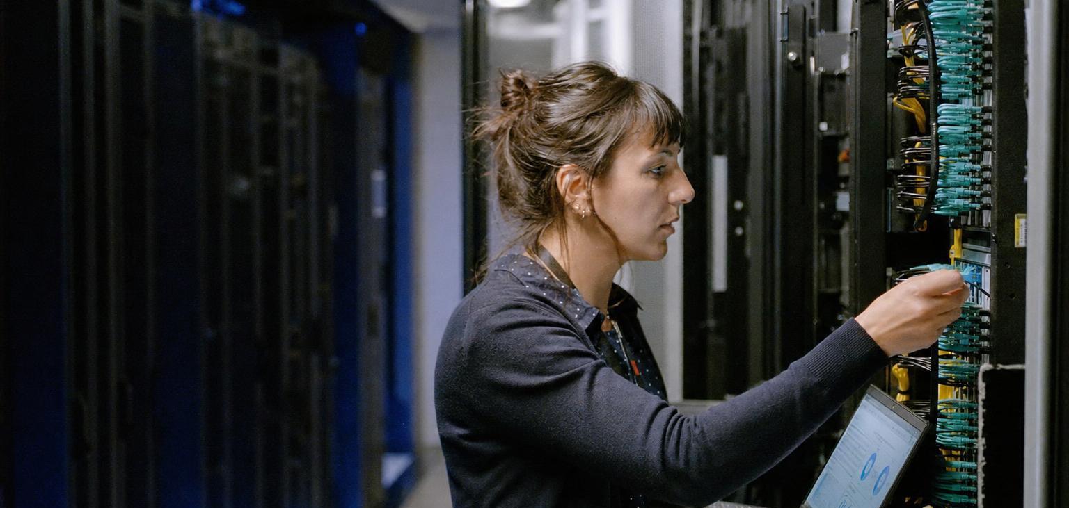 Une ingénieure réseau branche une jarretière optique dans un centre de données